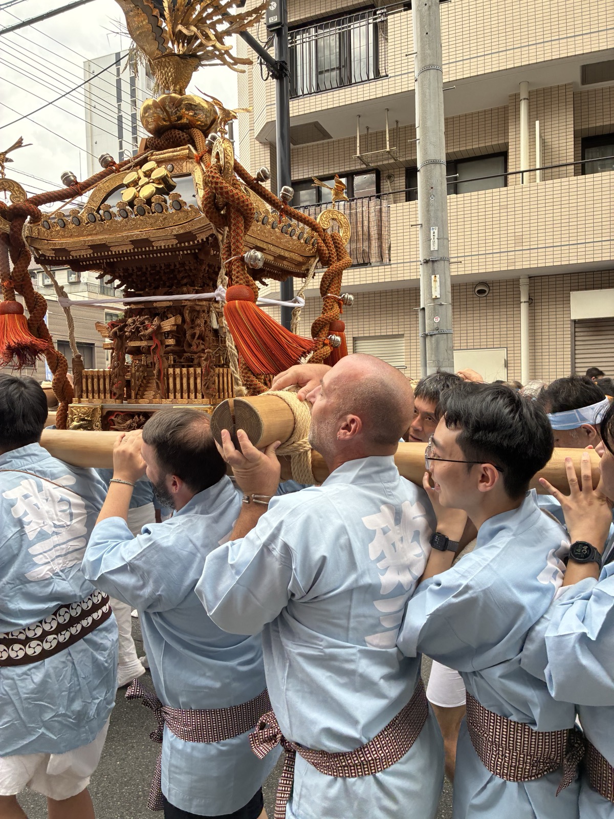 Guests lifting the golden mikoshi through the streets